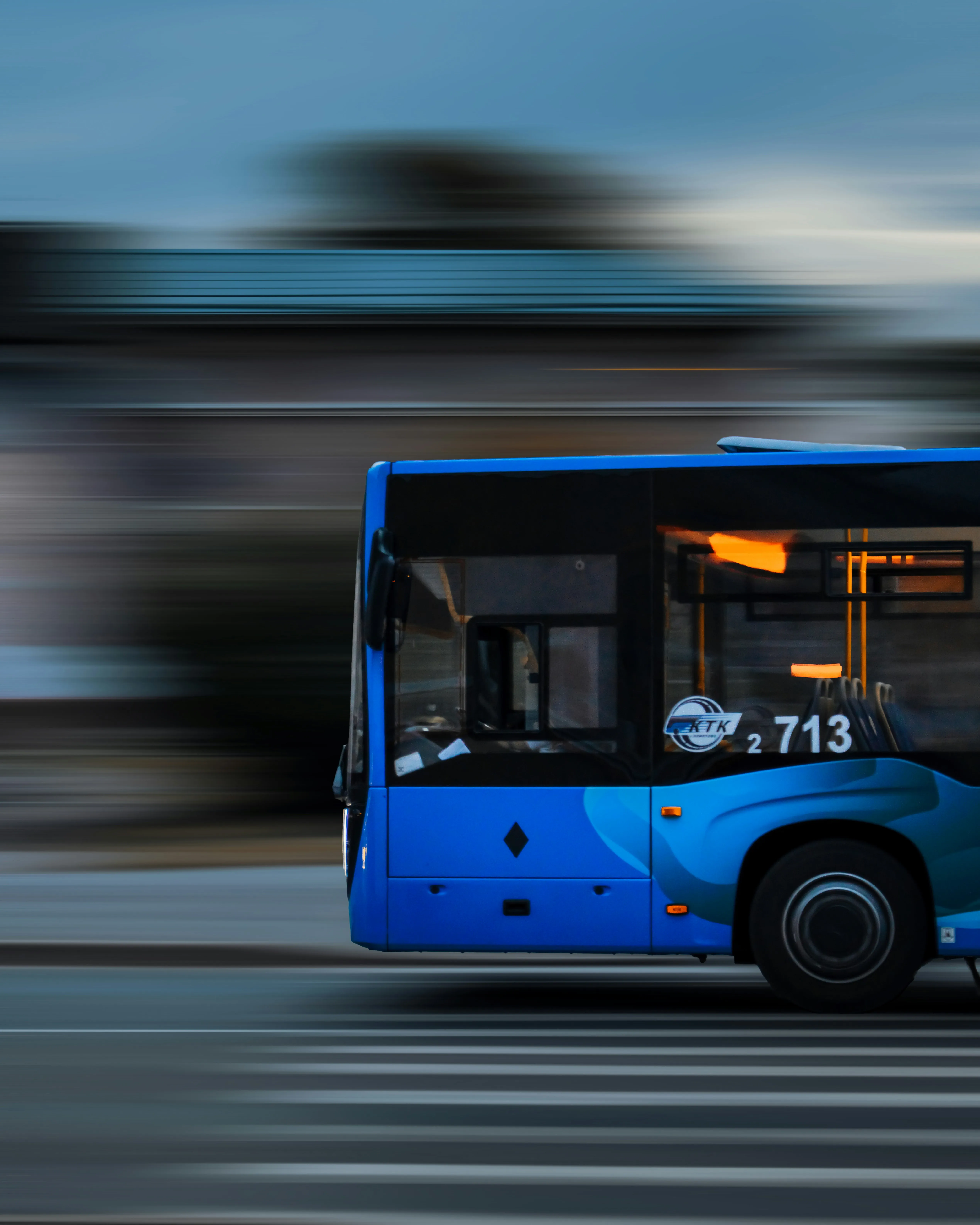 A blue coach bus driving on a mountain road.